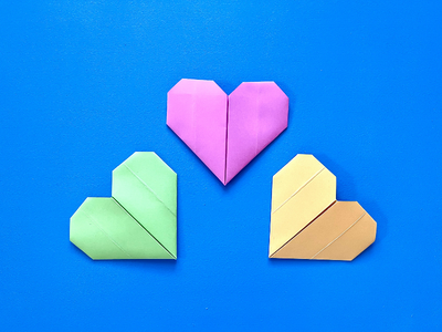 Three paper heart origami pieces on a blue background